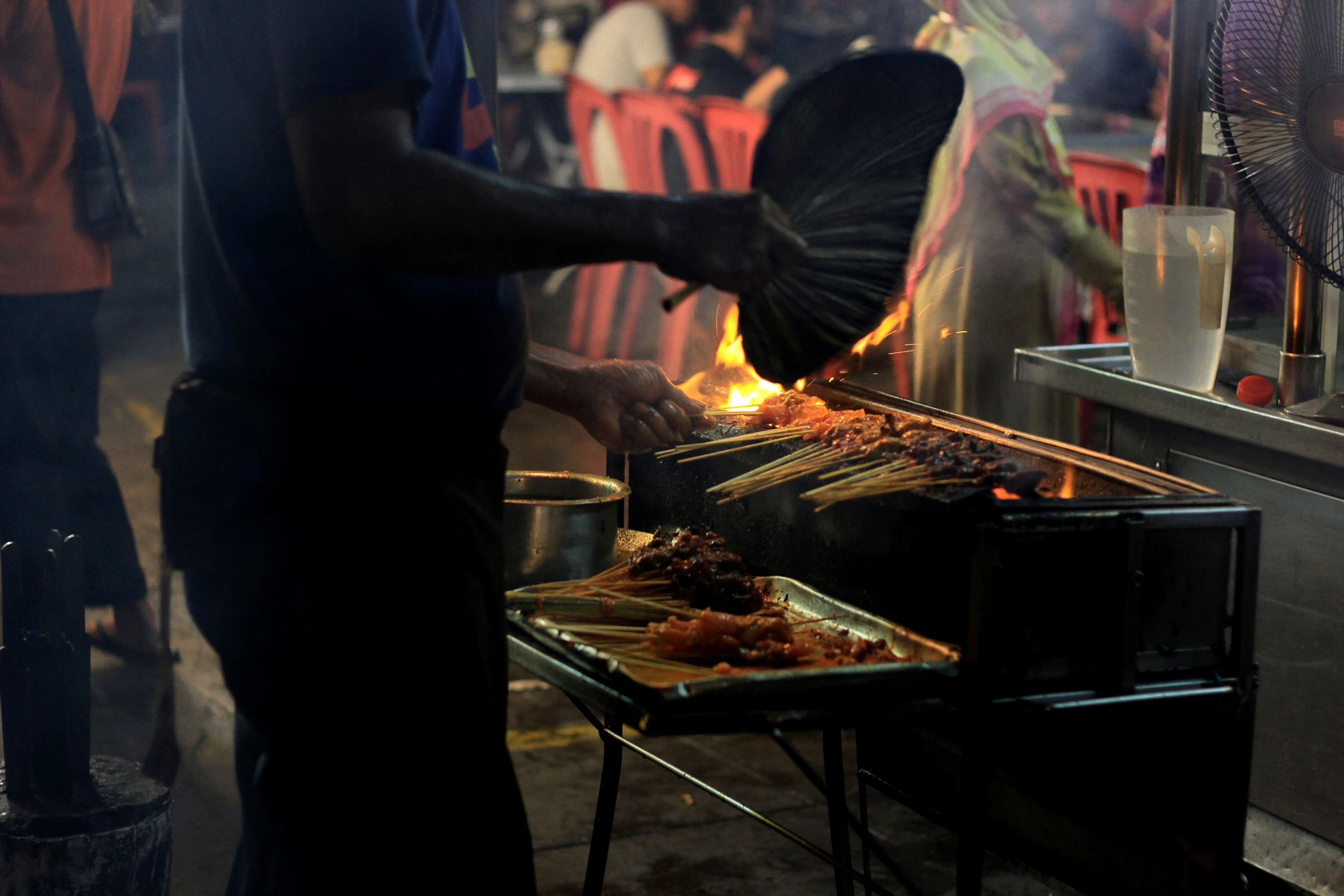 a man cooking on a grill with flames in front