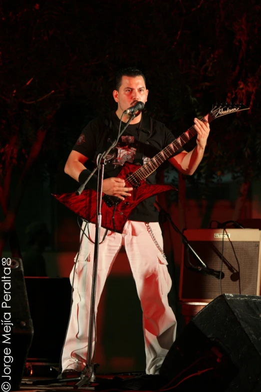 a man plays an electric guitar while standing on stage