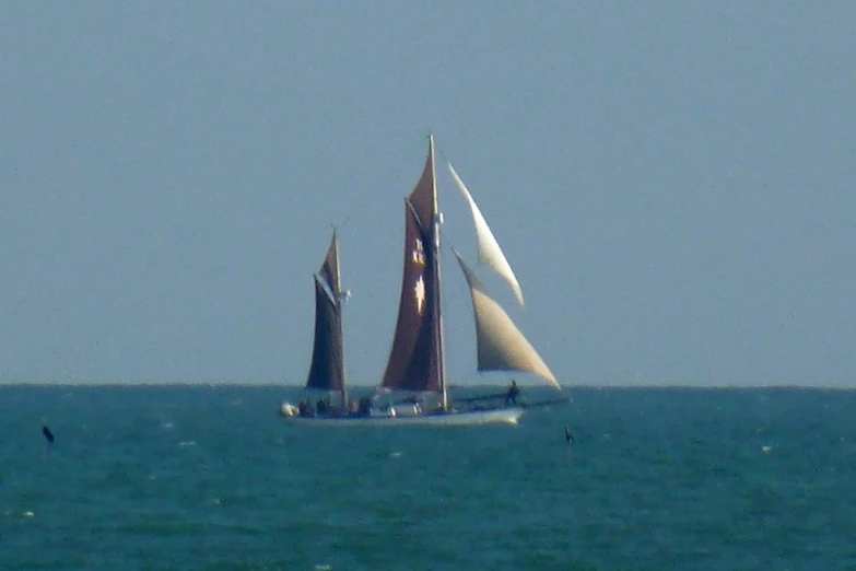 a sailboat with four sails traveling across the water