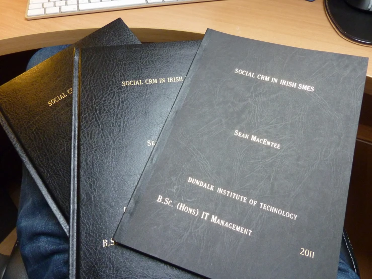 four black leather journals sitting on a desk