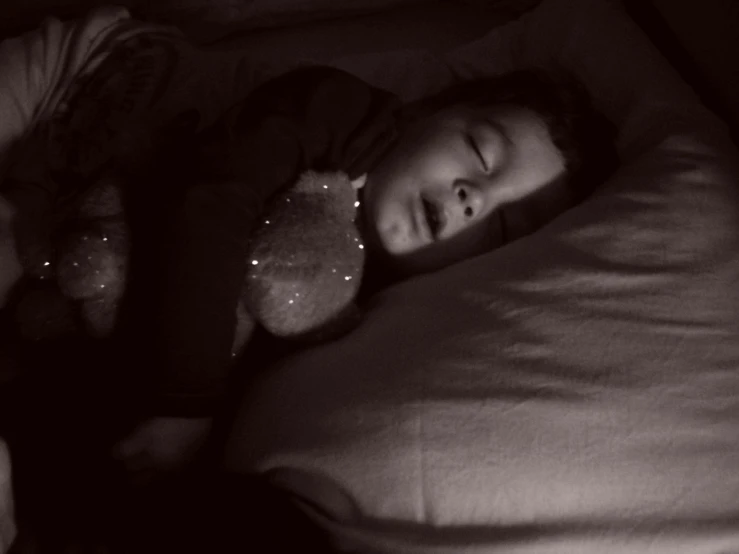 a young child is sleeping with her stuffed bear