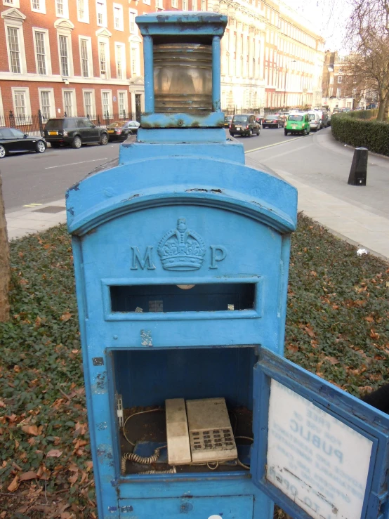 a blue mail box in the middle of a field of grass