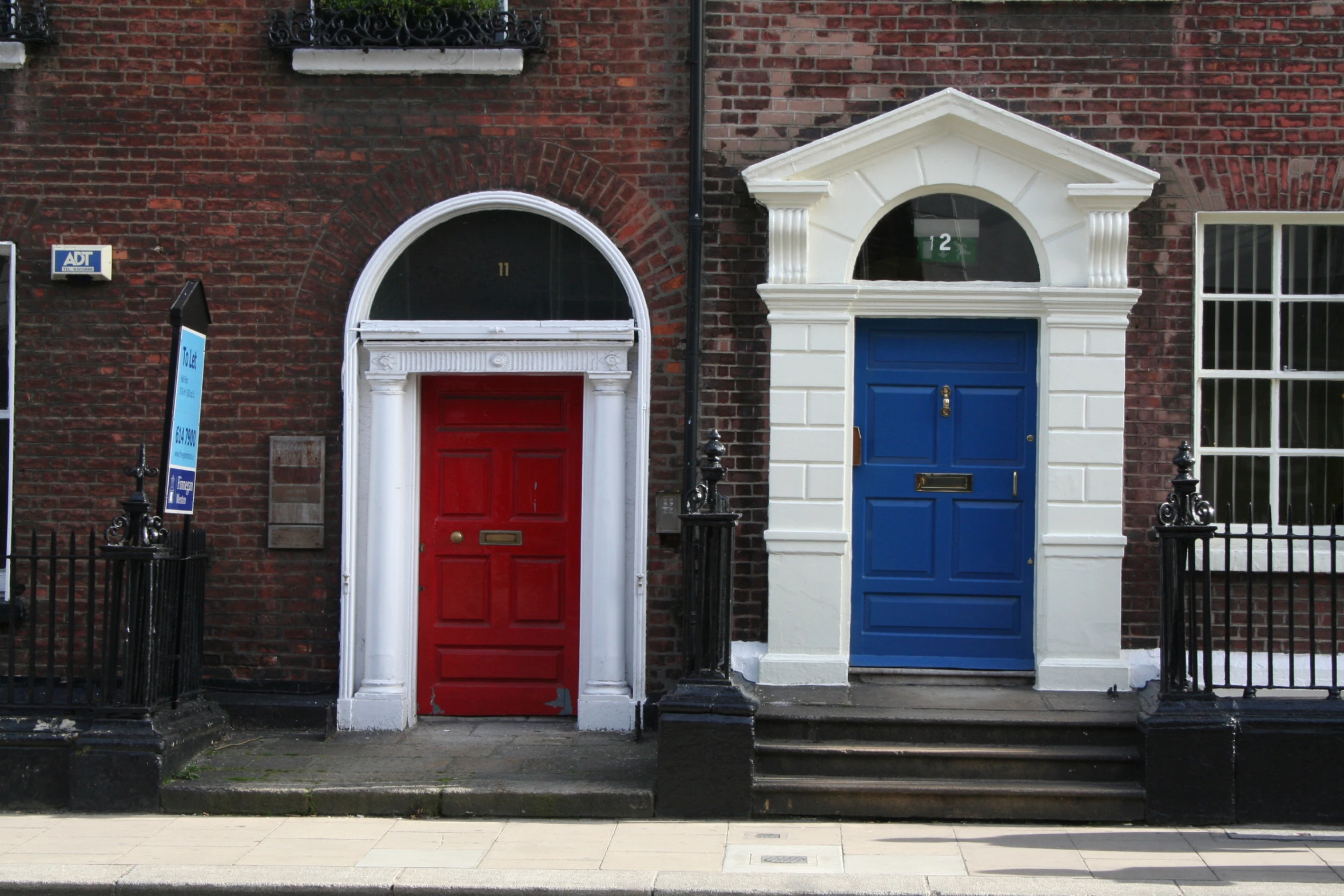 two red doors and a blue door with white trim, on a brick building