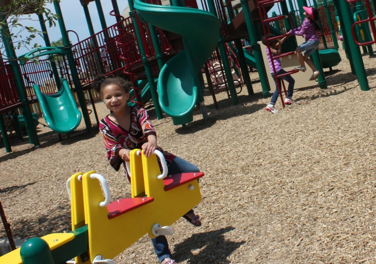 a little girl that is sitting on a playground