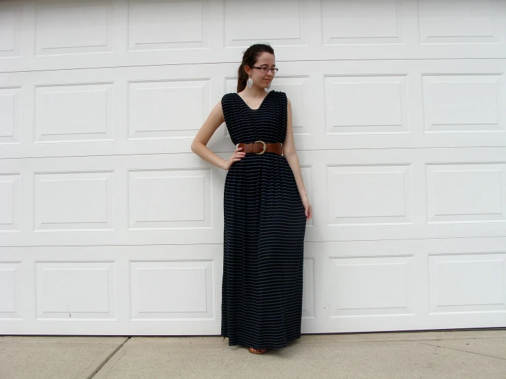 a girl stands against a wall, posing for the camera