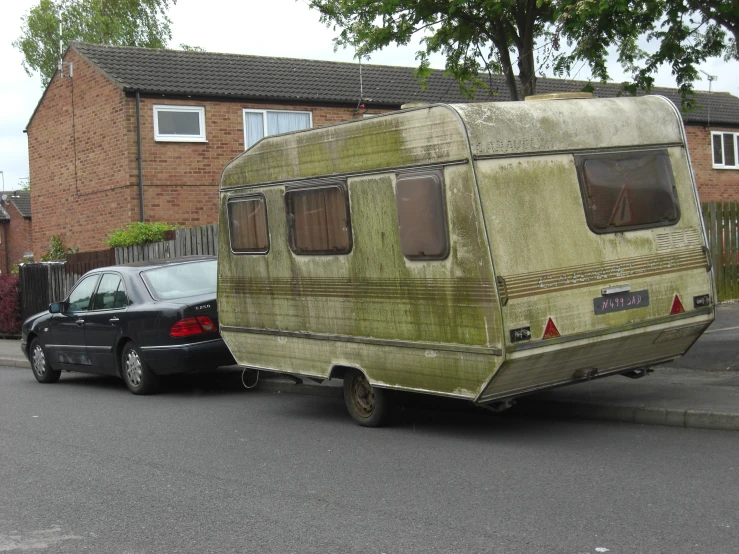 an old trailer is pulled into a parked car