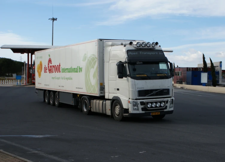 a large white truck with german language on the side driving down the street