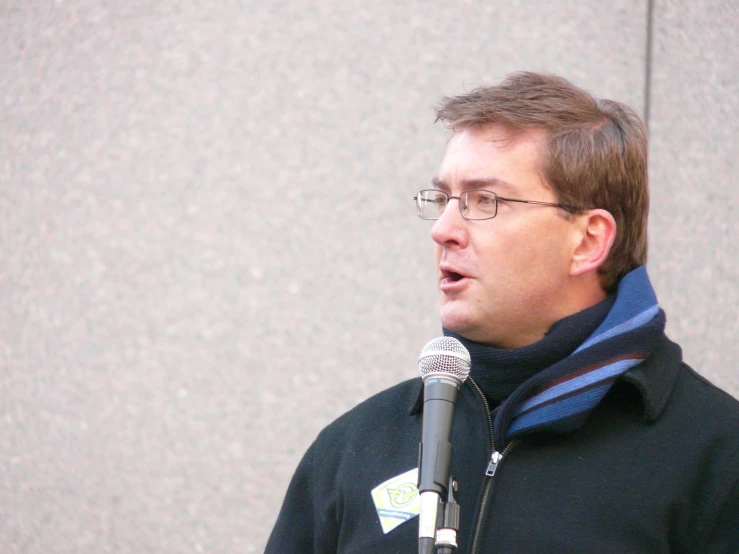 a man in a black sweater is talking into a microphone