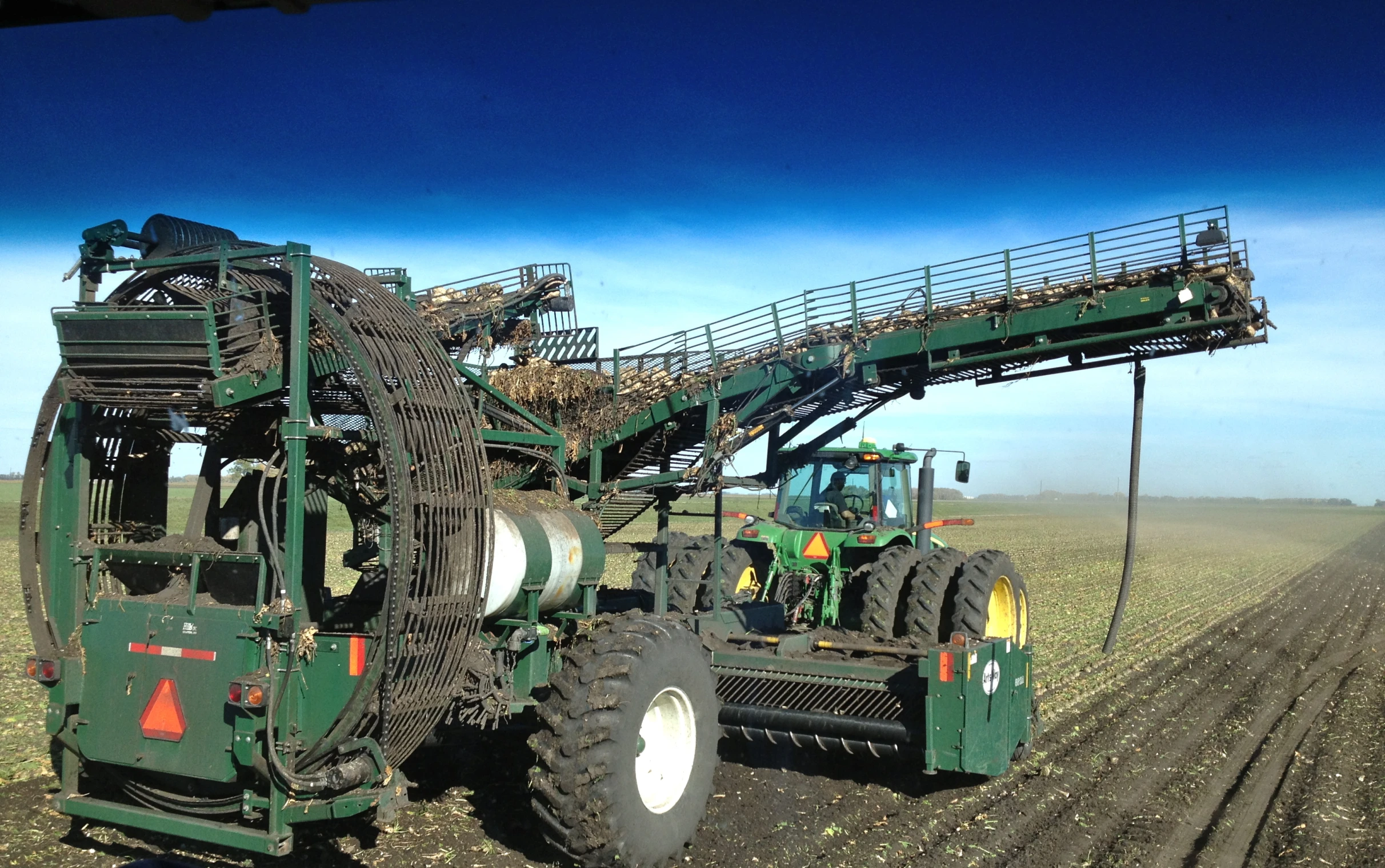 a tractor being loaded with metal pipes by a machine