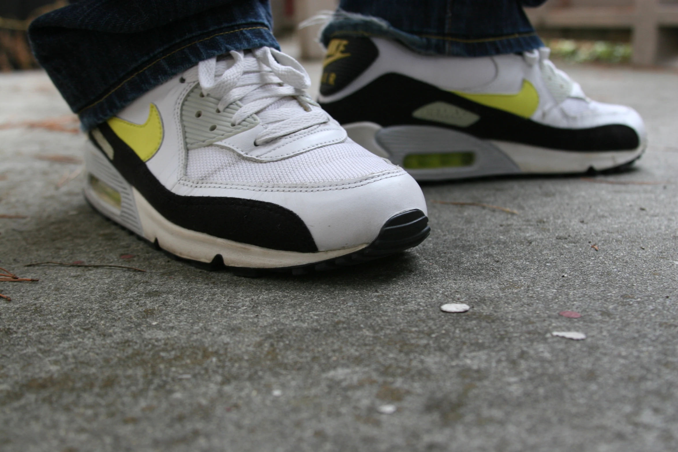 the nike air max white and yellow shoes on the sidewalk