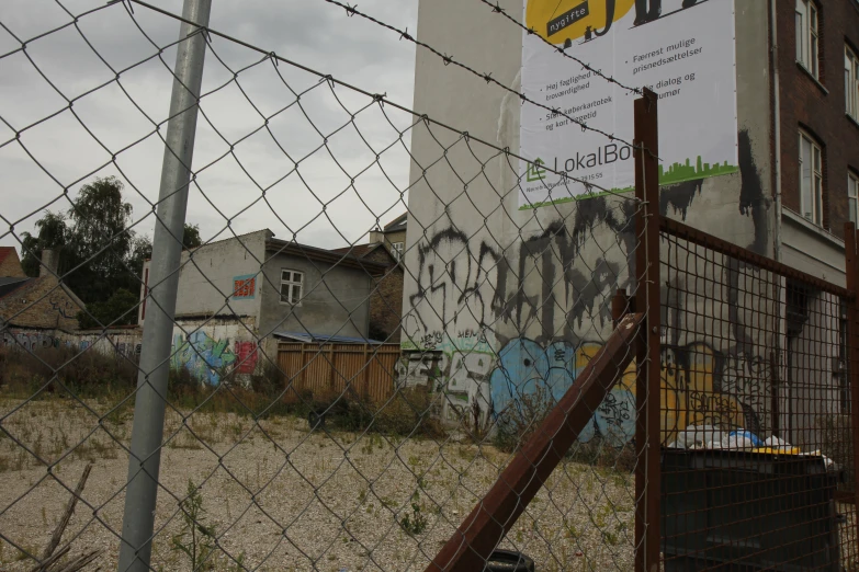 an overgrown industrial area with old buildings and barbed wire