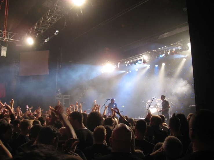 a large group of people at a concert with lights and fans