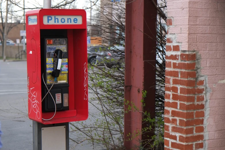 a red phone is standing on the curb