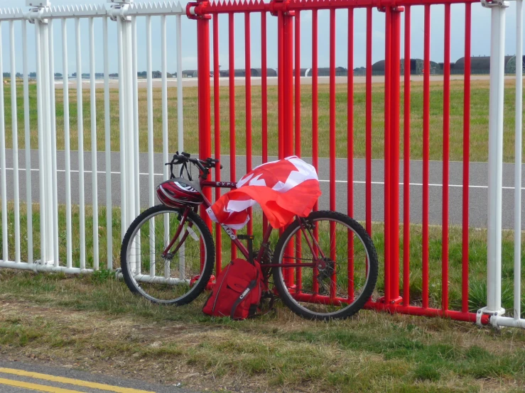 a bicycle  up against a red fence