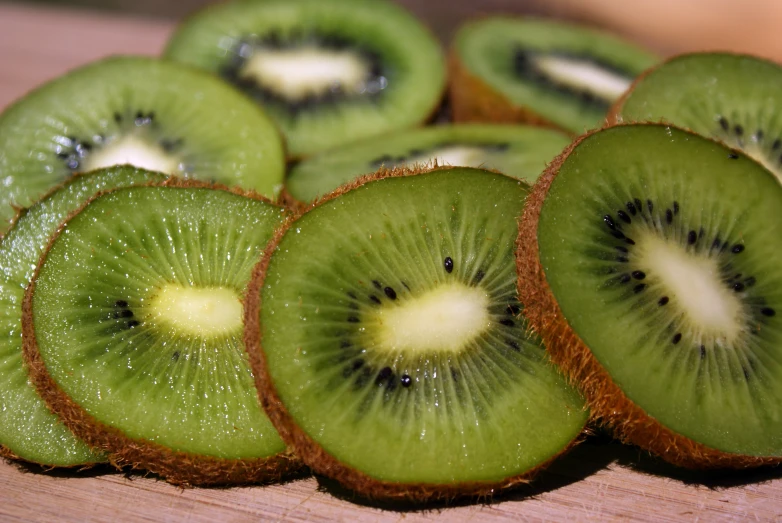 sliced kiwis that have been cut open are on a  board