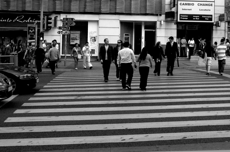 black and white pograph of people walking across the street