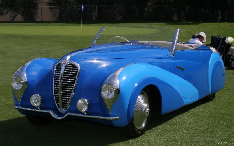 a bright blue sports car with two people in the back