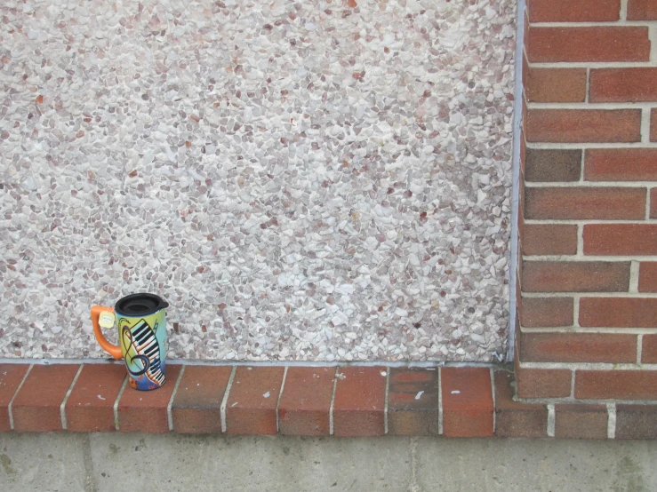 a cup sitting on the curb by a building