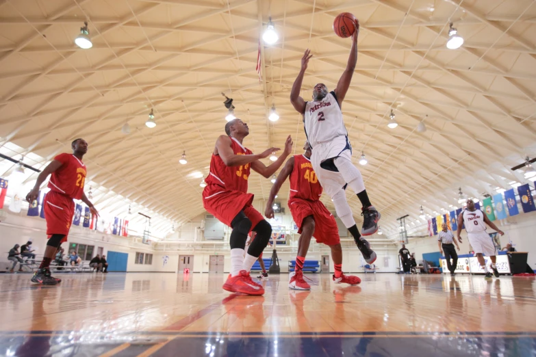 some men are playing basketball inside a large indoor gym