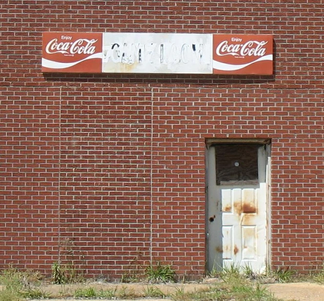 the red brick wall has a door and advertising for the company