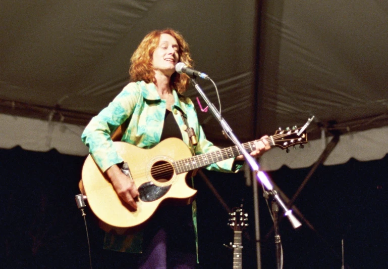 a woman that is holding a guitar on a stage
