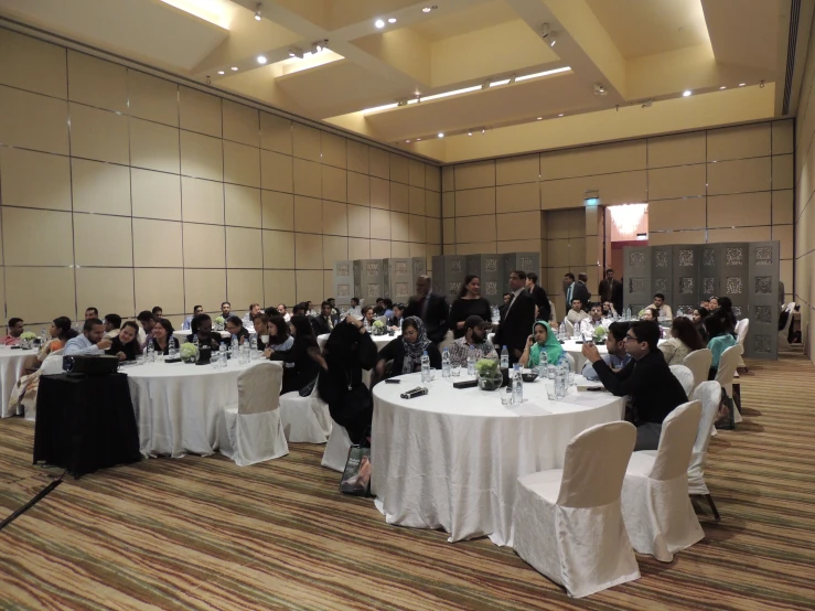 a conference room set up with tables and white clothed chairs