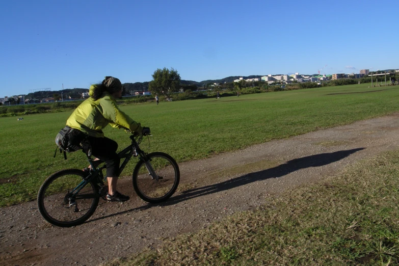 a person riding a bike on a dirt path in front of some grass