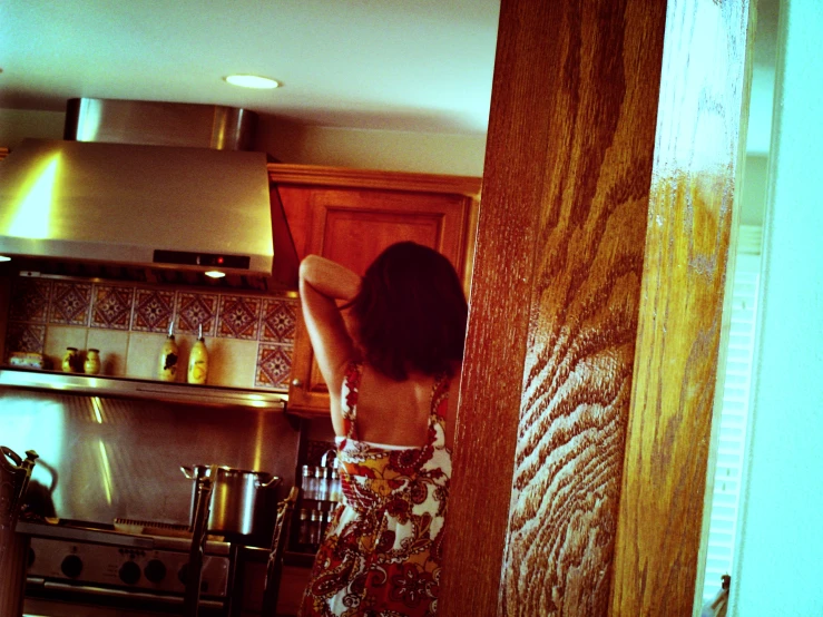 the back of a girl in a kitchen reaching up and pointing to the counter