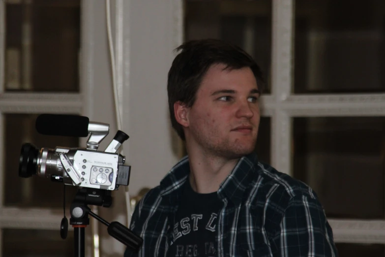a man is sitting with a camera on a tripod