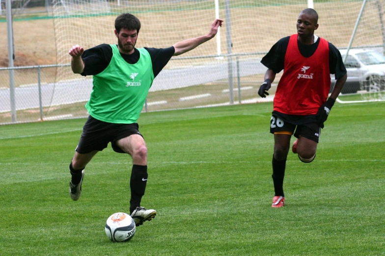 a man kicking a soccer ball next to another man