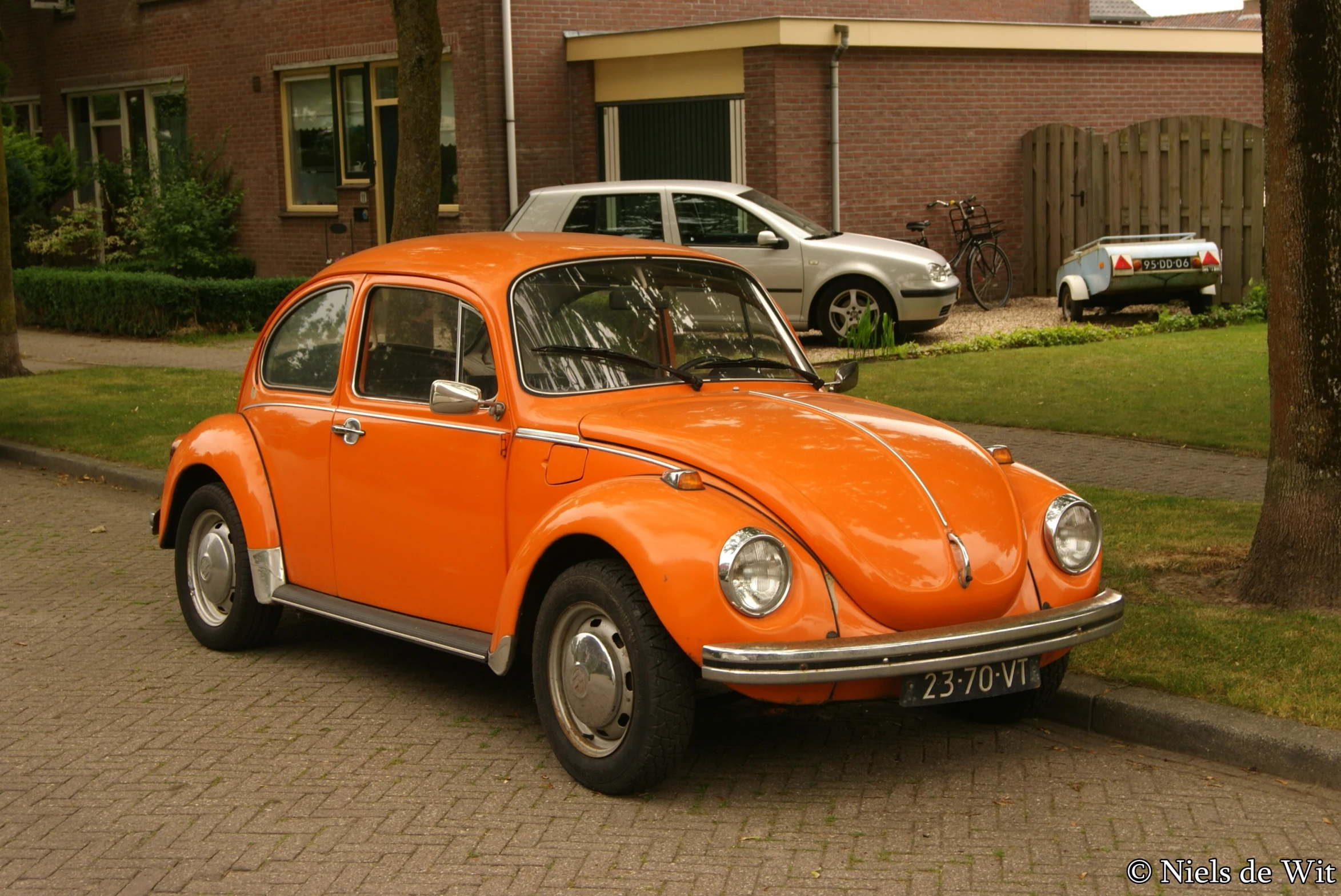 an orange volkswagen beetle is parked next to a house