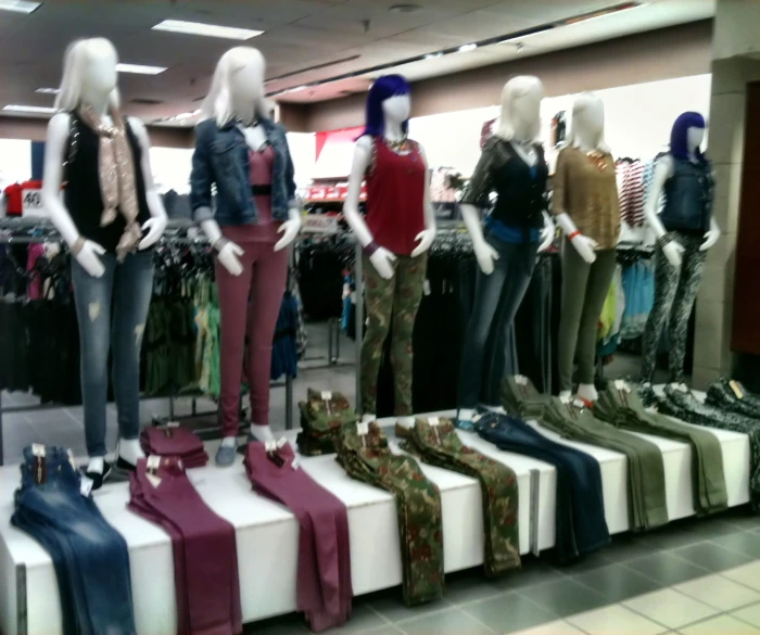 several mannequins dressed in different colored outfits in a store