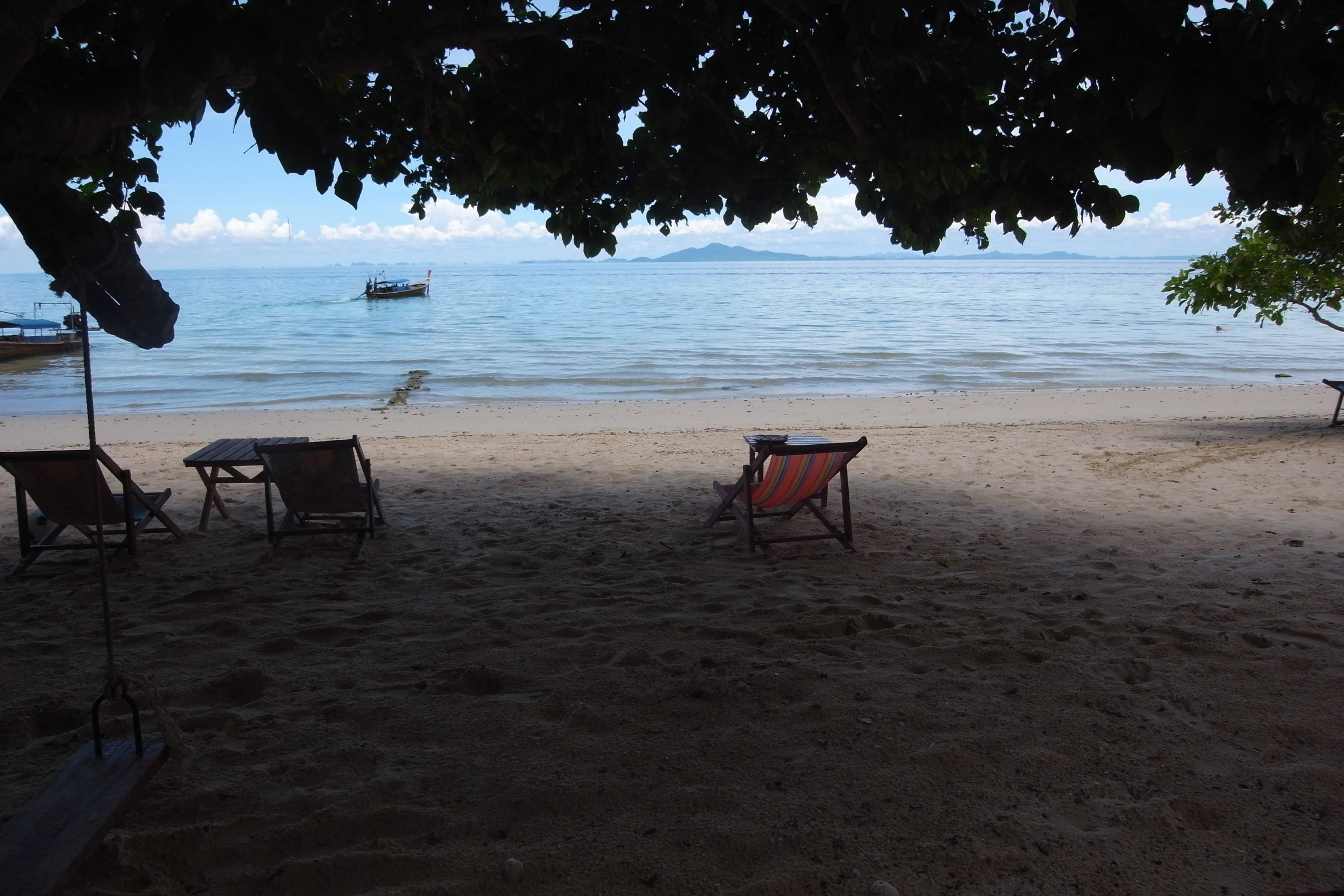 two beach chairs sitting on the sand under trees