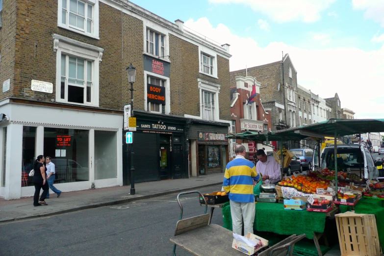 the fruit stands on the street in front of the shops