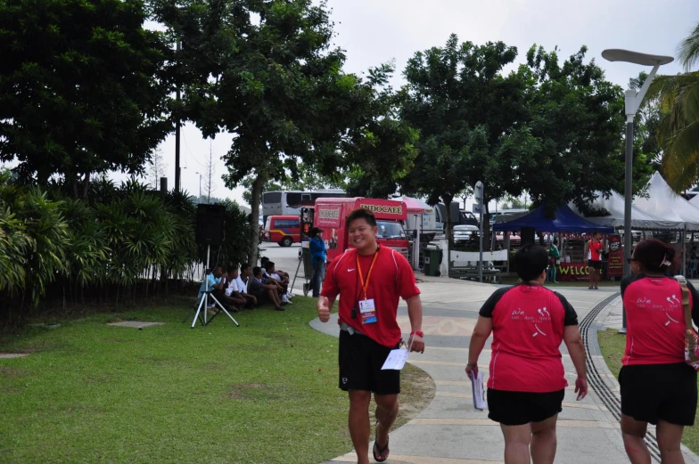 three people in red shirts stand on a sidewalk