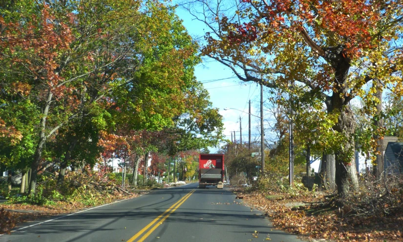 the truck is driving down the road in the fall