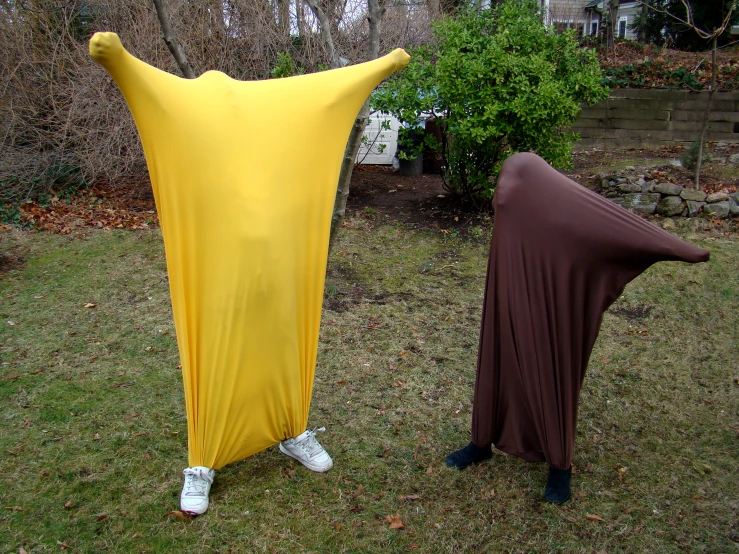 two people in costumes, one dressed as bananas and one wrapped in fabric