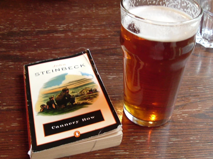 a book is sitting next to a glass of beer