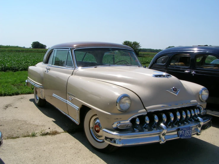 a classic beige automobile sitting in a parking lot