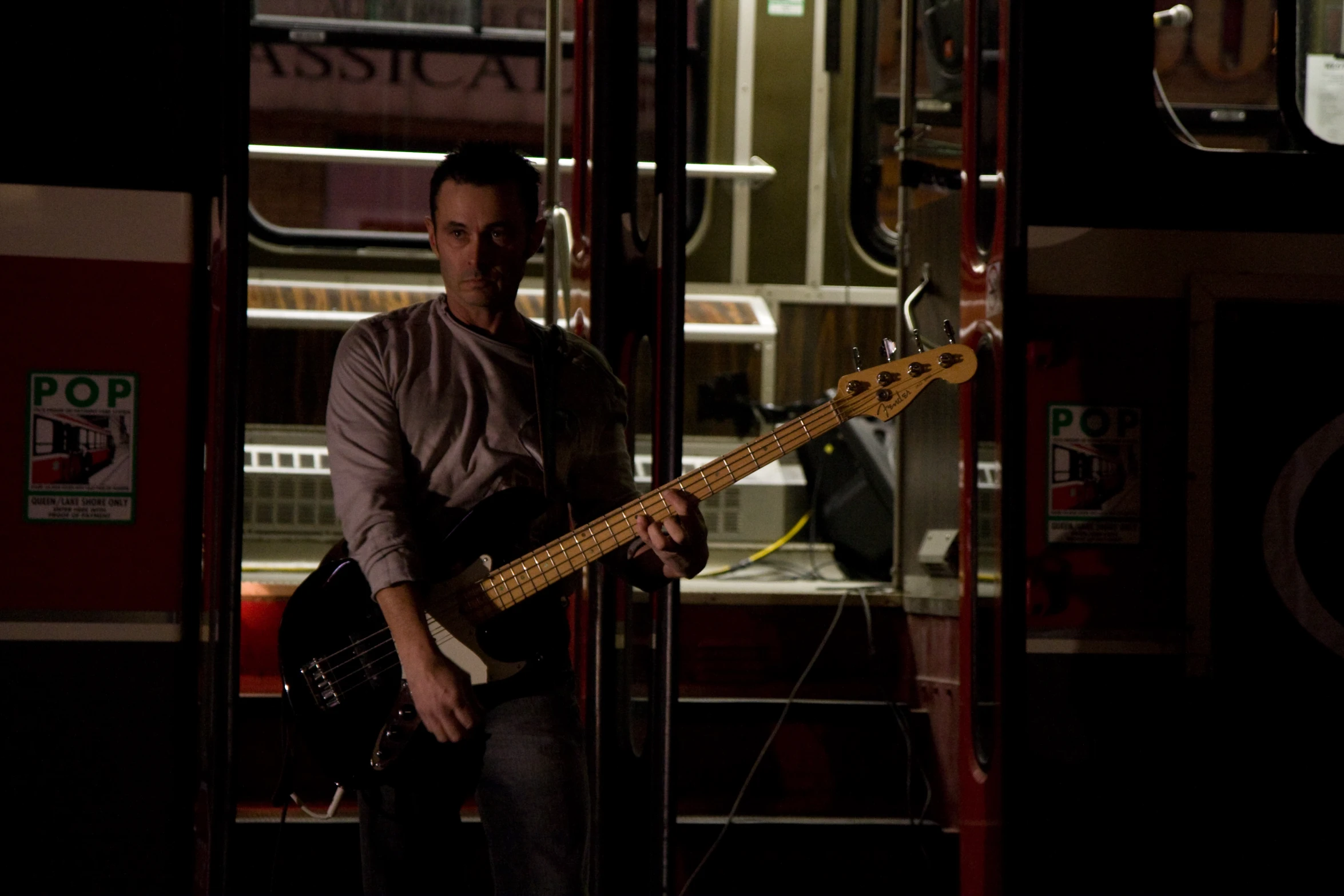 a man standing with his guitar on the bus