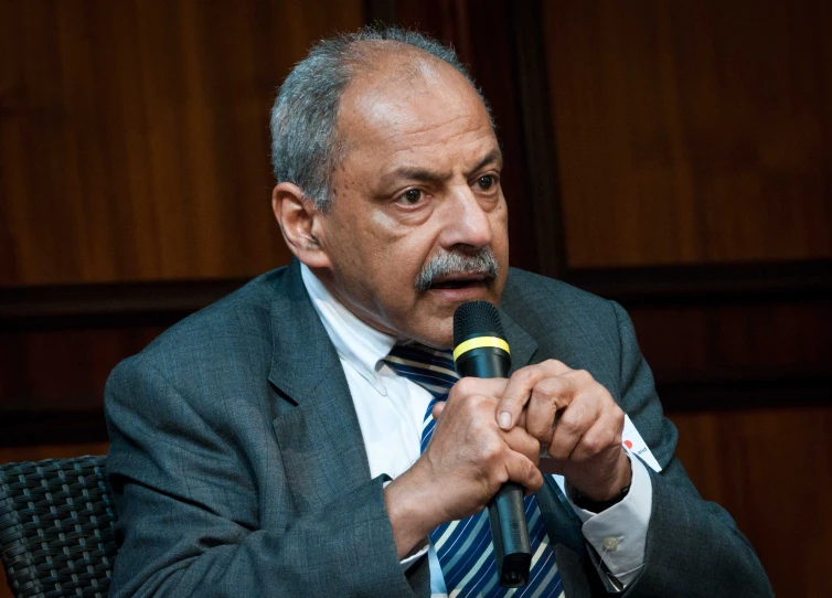 man holding microphone making funny face while sitting at table