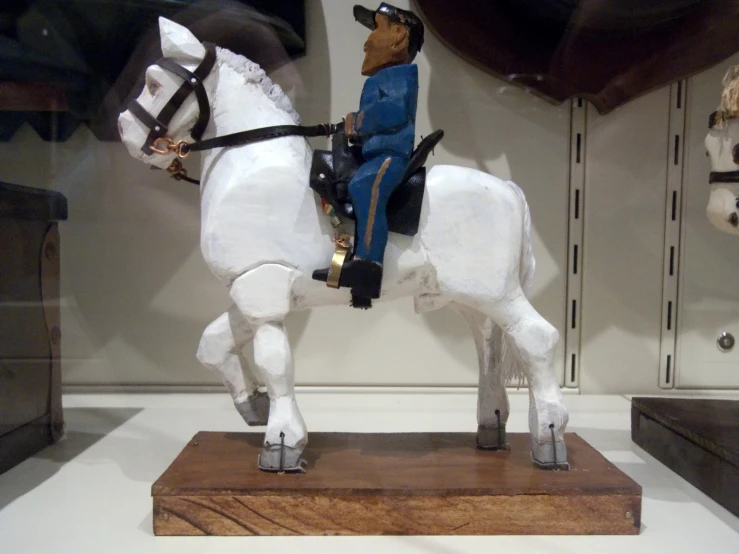 this is a white toy horse and man wearing blue