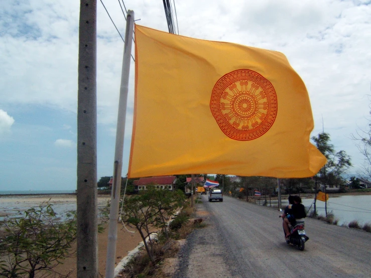 a motorcyclist in the road carrying a large flag