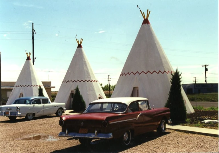 three old - fashioned cars are parked outside a tent