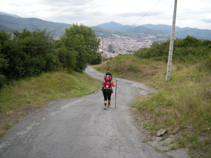 a man is hiking up the road with a backpack