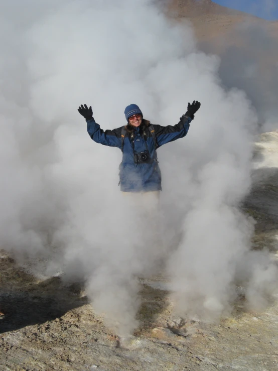 a person standing on the top of a hill by a mountain in smoke