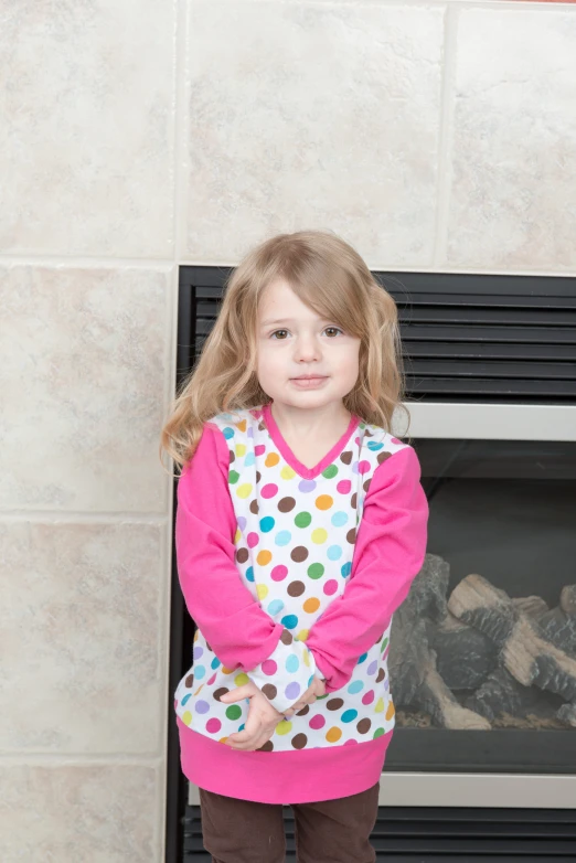 a small girl standing next to a fire place