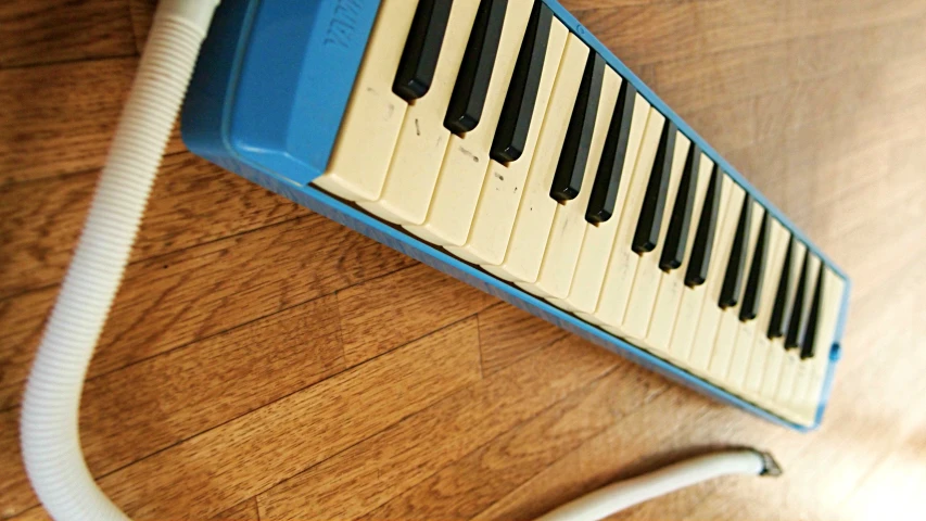 a blue and white music keyboard laying on the floor