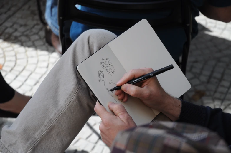 a man sitting down while writing on his notebook