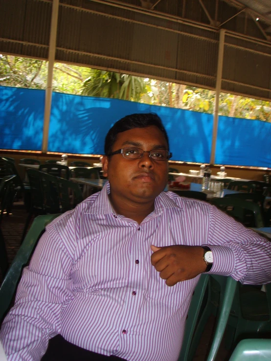 the man sitting in the stands has his hands clasped to his chest